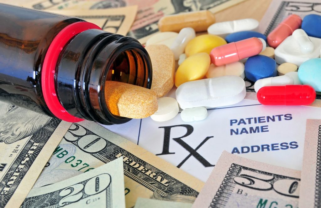 Pill bottle, pills, dollars and a prescription pad